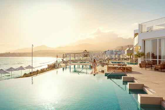 En kvinna vid en infinitypool med havet och en bergskedja i bakgrunden. (AI-genererad text)