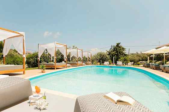 En swimmingpool med bäddar och parasoller runt omkring. (AI-genererad text)