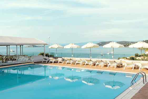 En pool med solstolar och parasoller vid havet. (AI-genererad text)