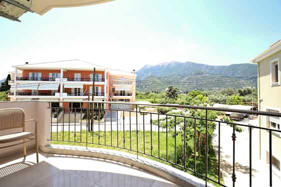 Utsikt från en balkong med en stol, en gräsmatta och byggnader i bakgrunden. (AI-genererad text)