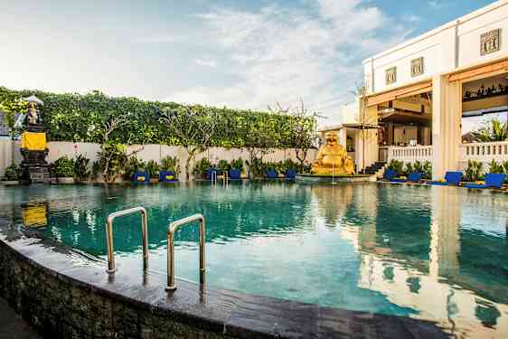 En inbjudande pool omgiven av solstolar och grönska, med en gyllene staty som dekoration. (AI-genererad text)