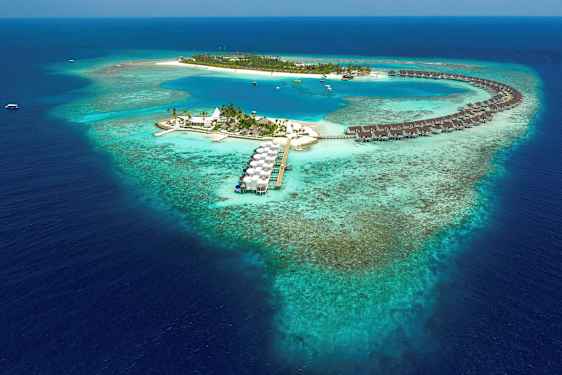 Flygfoto av en tropisk ö med övervattensbungalower och blå lagun omgiven av korallrev. (AI-genererad text)