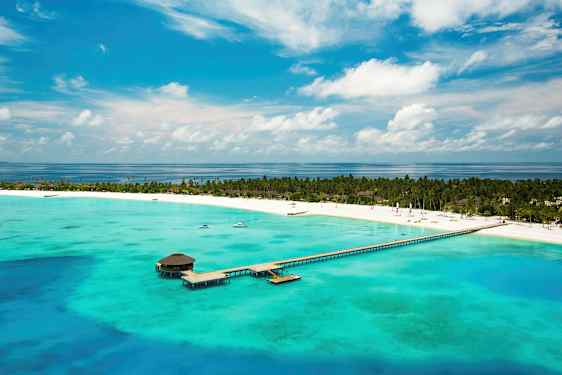 Flygvy över en tropisk strand med brygga som sträcker sig över turkost vatten. (AI-genererad text)