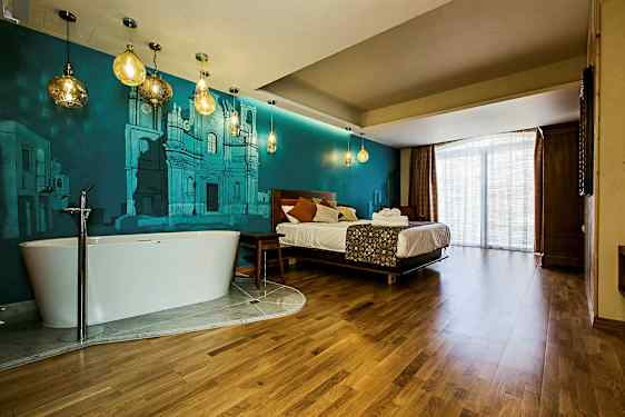 Ett hotellrum med en säng, ett fristående badkar, och blå väggmålningar. (AI-genererad text)