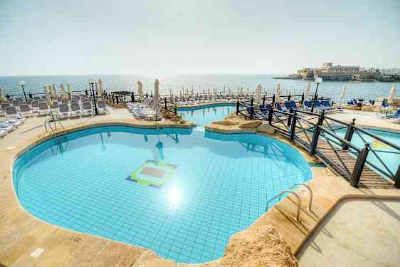 Bild av en utomhuspool vid stranden med solstolar och parasoll runt omkring. (AI-genererad text)