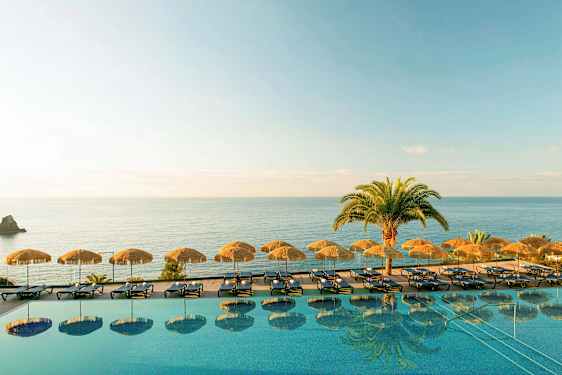 En infinitypool med solsängar och parasoller vid havet. (AI-genererad text)