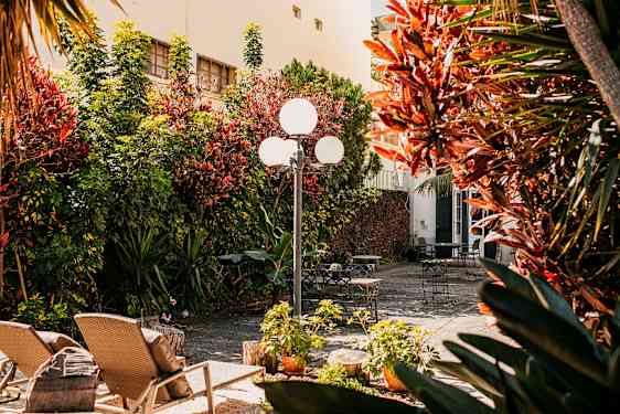 En solig innergård med trädgårdsmöbler och grönska. (AI-genererad text)