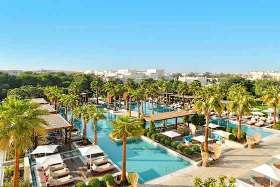 Ett lyxigt poolområde omgivet av grönska och palmer, med solstolar och parasoller. (AI-genererad text)