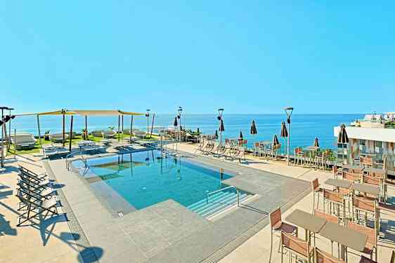 Utomhuspool med solstolar och parasoller samt havsutsikt. (AI-genererad text)