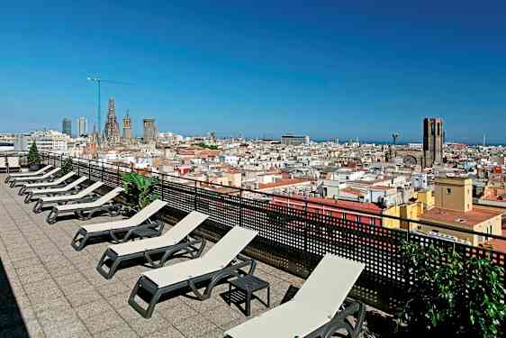 En takterrass med solstolar och utsikt över en stad med kyrka och blå himmel. (AI-genererad text)