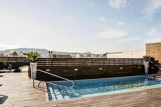 En takterrass med en pool, omgiven av träpaneler och med utsikt över en stad. (AI-genererad text)