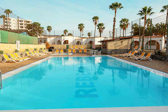 Utomhuspool med solstolar och palmer i bakgrunden. (AI-genererad text)