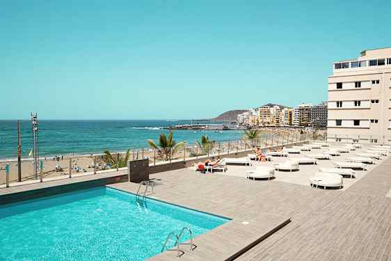 Utsikt över en pool och en strand med hav i bakgrunden. (AI-genererad text)