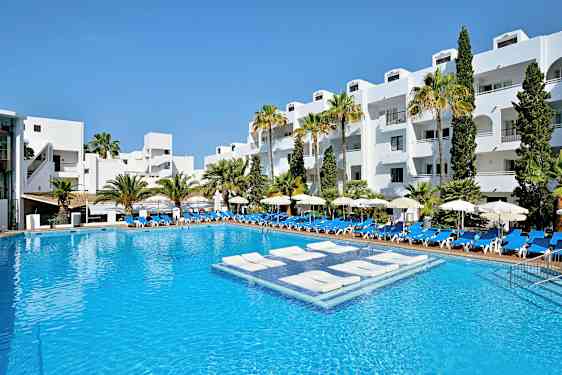 En hotellpool med vitmålade byggnader och palmer i bakgrunden. (AI-genererad text)