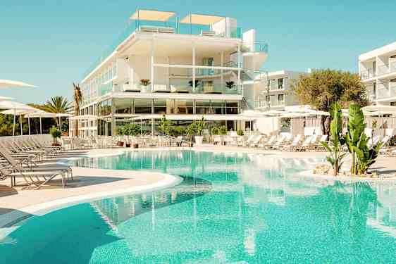 Ett modernt hotell med glasbalkonger ligger vid en klarblå pool med omgivande solstolar och gröna växter. (AI-genererad text)