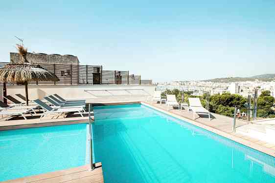 En swimmingpool på en terrass med solstolar och utsikt över en stad. (AI-genererad text)