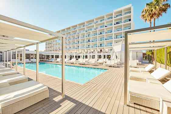 En modern hotelldesign med en pool omgiven av solstolar och parasoller, med ett stort vit byggnad i bakgrunden. (AI-genererad text)