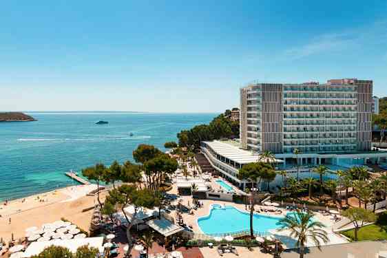 Flygfoto av ett hotellkomplex vid havet med pooler, grönska och en strand. (AI-genererad text)