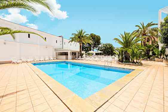 Bild som visar en pool med ljusblått vatten, omgiven av en solterrass med solstolar och palmer. (AI-genererad text)