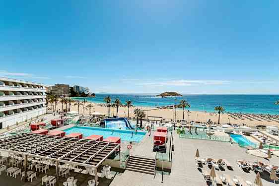 Bild av en solig strand med palmer, turkost vatten och en pool i förgrunden. Byggnader syns till vänster. (AI-genererad text)