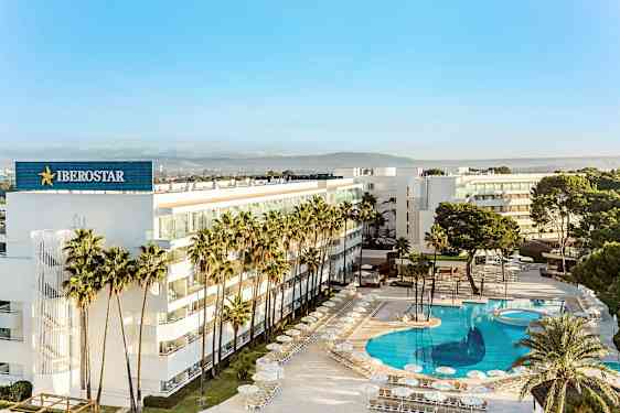 Ett modernt hotell omgärdat av palmer med en stor, klarblå pool. (AI-genererad text)