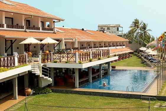 Hotell med utomhuspool, terrasser och solstolar. En person simmar i poolen. (AI-genererad text)