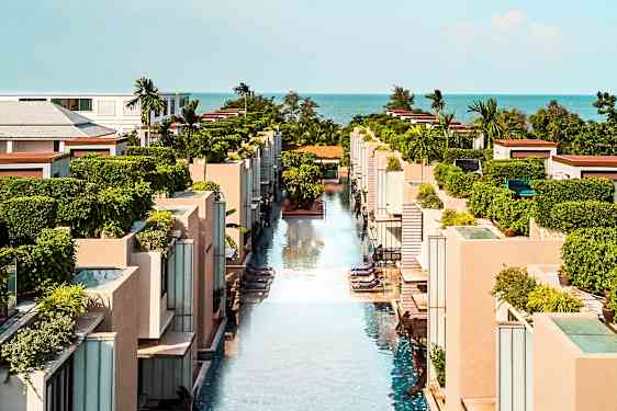 En vy över en modern semesteranläggning med pooler och grönska. (AI-genererad text)