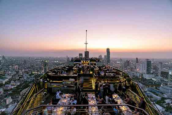 Takbar vid solnedgång med restauranggäster och panoramautsikt över stadens skyline. (AI-genererad text)