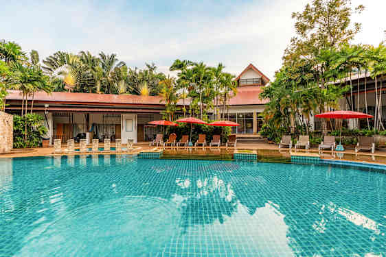 En pool med klarblått vatten, omgiven av solstolar med röda parasoller och gröna palmer i bakgrunden. (AI-genererad text)