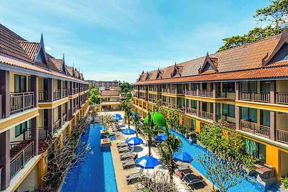 Två våningar höga hotellbyggnader med sluttande tak omger en pool med solstolar och parasoller. (AI-genererad text)