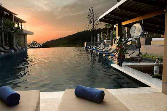 En infinitypool med liggstolar och handdukar på en resort vid solnedgången. (AI-genererad text)