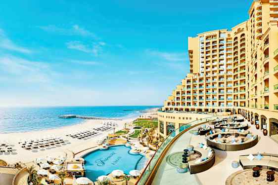 Ett hotell belägen vid strandkanten med pool och solstolar på stranden. (AI-genererad text)