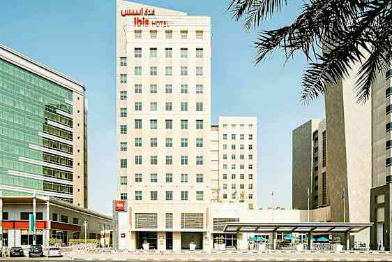 En hotellbyggnad med modern design mitt i en stadsmiljö, omgiven av andra byggnader. (AI-genererad text)