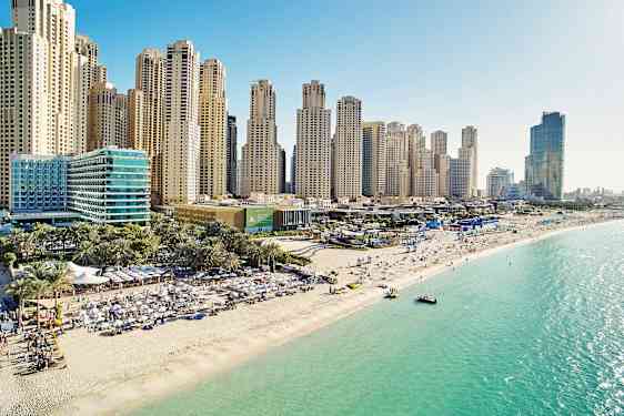 Strand med folk som njuter av solen, höga skyskrapor i bakgrunden och klart turkost vatten. (AI-genererad text)