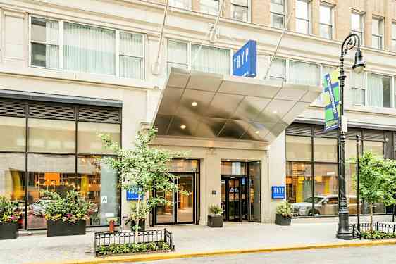 Entré till ett hotell med skylt texten "TRYP". Byggnaden har stora fönster och planteringar. (AI-genererad text)