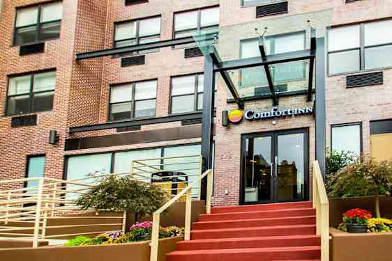 Entrén till en byggnad med texten "Comfort Inn" ovanför dörren. (AI-genererad text)