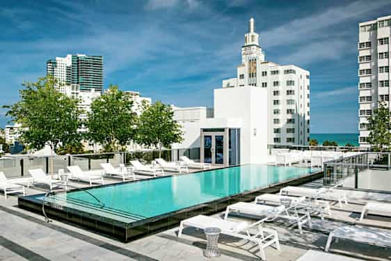 En takpool med solstolar runtom, omgiven av moderna byggnader och grönska. (AI-genererad text)