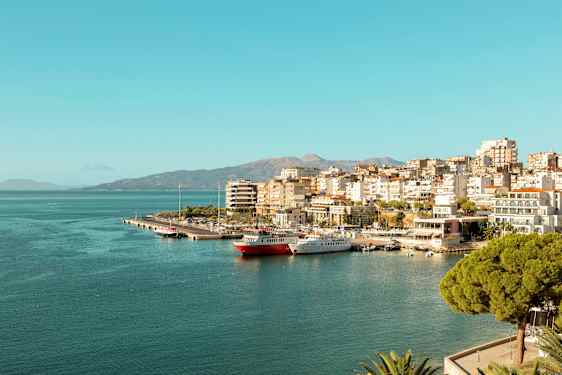 Vy över en stad vid havet med småbåtshamn och byggnader längs kusten. (AI-genererad text)