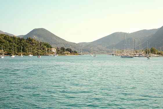 En vy över en vik med segelbåtar och omgivande gröna kullar. (AI-genererad text)