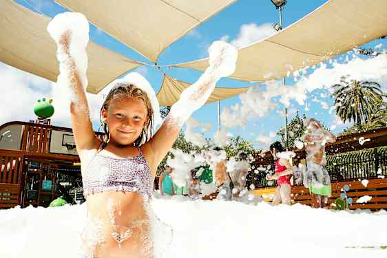 En grupp människor njuter av en skummig aktivitet under ett skärmtak utomhus. (AI-genererad text)