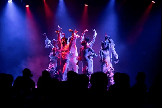 Dansare framför en koreografi på en scen med färgad ljussättning. (AI-genererad text)