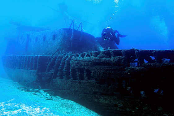 En undervattensfotografi av ett sjunket fartyg med en dykare som simmar bredvid. (AI-genererad text)