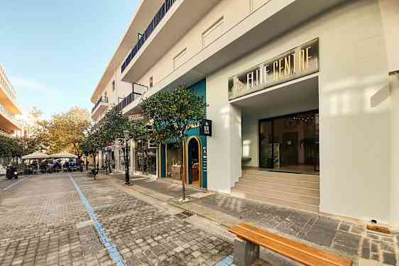 Ett gatumotiv med butiker och kaféer längs en stenlagd promenadsträcka. (AI-genererad text)