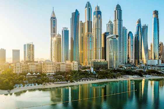 Skyline med höga byggnader och en strand vid vatten i förgrunden. (AI-genererad text)