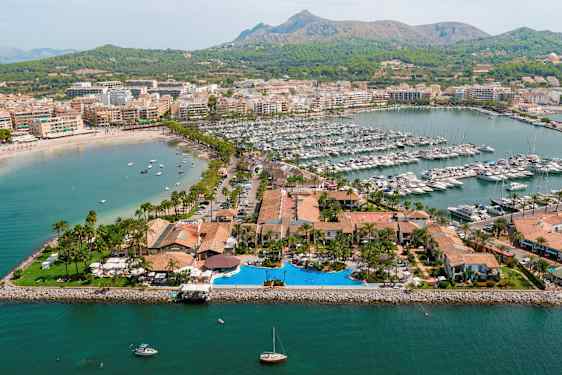 Flygbild över en hamnområde med båtar och omgivande byggnader. (AI-genererad text)