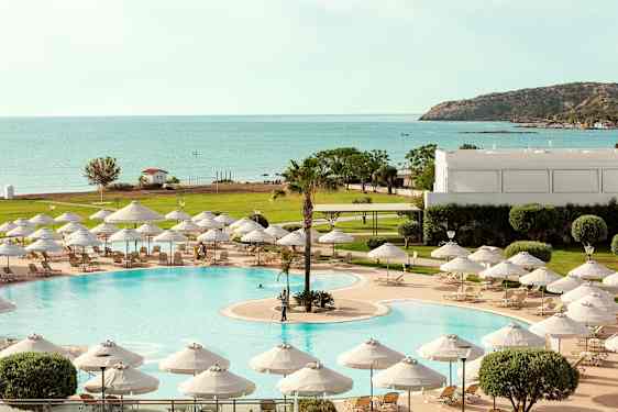 En pool med solstolar och parasoll, med utsikt mot havet och en grönskande omgivning. (AI-genererad text)