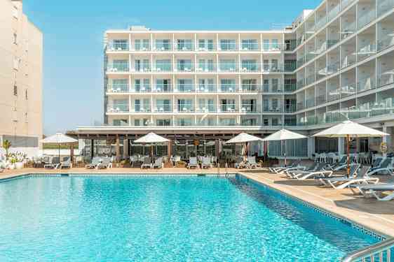 En byggnad med flera balkonger, framför en pool med solstolar och parasoller. (AI-genererad text)