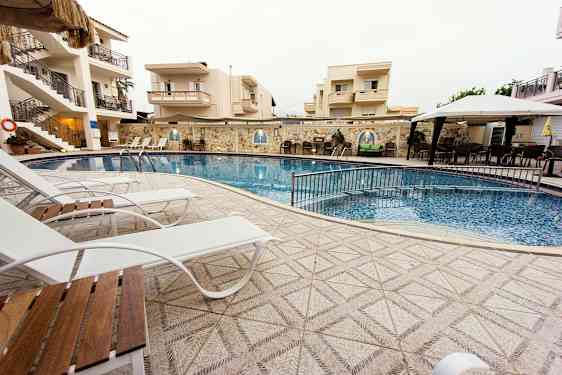 Utomhuspool vid hotell, omgiven av solstolar och byggnader. (AI-genererad text)