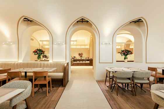 En elegant restaurang med bågformade fönster, trästolar och bord samt blomsterdekorationer. (AI-genererad text)