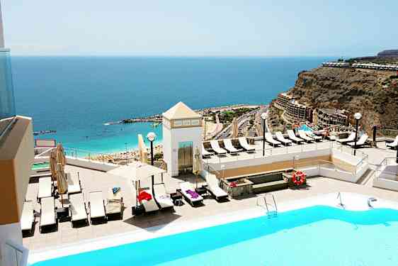 Poolområde med utsikt över havet och en strand. (AI-genererad text)